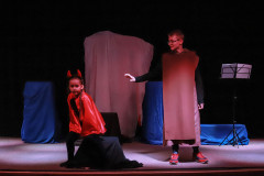 Podczas spektaklu. Po lewej dziewczynka przebrana za diabła. Ubrana w czerwoną pelerynę i rogi. Po prawej chłopiec w brązowej tunice.