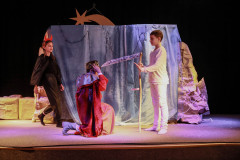 Fragment spektaklu. Na scenie od lewej: dziewczynka przebrana za diabła, klęczący król, a przed nim chłopiec w bieli z kosą.