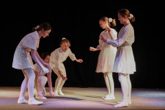 Fragment spektaklu. Na scenie pięcioosobowa grupa. Dziewczyny w białych sukienkach i rajstopach.