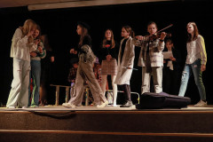 Fragment spektaklu. Na scenie grupa młodzieży w strojach współczesnych. Jedna z dziewczyn gra na skrzypcach.