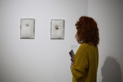 Daria Mach widziana tyłem ogląda prace wyeksponowane na ścianie.