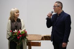 Po lewej Alicja Majewska z bukietem kwiatów, po prawej Robert Brzęcki z mikrofonem.