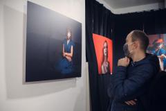 Mężczyzna przygląda się zdjęciu przedstawiającemu dziewczynę w niebieskiej sukience wyłaniającą się z czarnego tła.