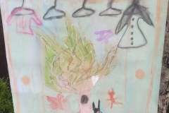 Rysunek wykonany suchymi pastelami. Przedstawia drzewo, a nad nim rząd wieszaków.