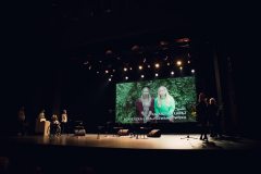 Mrok sceny, światła reflektorów i wyświelony film z wypowiedzią Katarzyny Łapaj i Agnieszki Łapaj-Lewandowskiej.