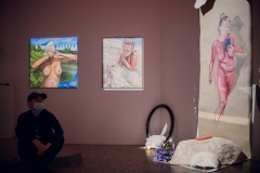 Obrazy artystki. Od lewej: naga kobieta widziała od pasa w górę,  autoportret malarki leżącej na piasku oraz  kobieta o różowej skórze, która trzyma telefon.