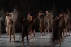 Scena grupowa. Tancerze w układzie choreograficznym. Wyraźnie widać jedynie ich stopy, reszta sylwetek rozmyta. Zdjęcie z efektem malowania światłem.