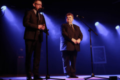 Na scenie przy mikrofonach burmistrz Mariusz Zaborowski i Michał Chmielewski, dyrektor MGOK w Ślesinie. Za nimi światła reflektorów.