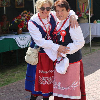 Dwie kobiety w strojach ludowych obejmują się i pozują do zdjęcia.