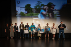 Nagrodzeni, jurorzy i organizatorzy na scenie. W tle wyświetlony slajd ze zdjęciem z nr 13.