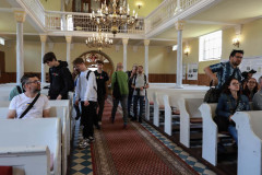 Uczestnicy spaceru zajmują miejsca w ławkach w kościele ewangelicko-augsburskim.