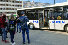 Grupa osób przed białym autobusem z niebieskim napisem PKS Konin. W tle bloki.
