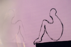 Fragment białego płótna z czarnym konturem człowieka, który siedzi bokiem.