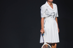 Agnieszka Przepiórska jako Ginczanka. Stoi na scenie w białym stroju z rakietą tenisową.