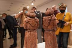 Widziane plecami dwie rzeźby zakonników. W tle nieostre postaci zwiedzających.