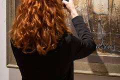 Odwrócona plecami rudowłosa kobieta w czarnym żakiecie robi telefonem zdjęcie jednej z  prac, przedstawiającej manekiny krawieckie. Kto pracuje w CKiS wie, że to Daria Mach.