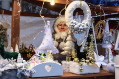 Kobieta w futrzanej czapce na stoisku z ozdobami świątecznymi.