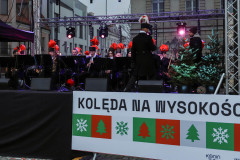 Orkiestra górnicza na scenie na placu Wolności w Koninie. Na pierwszym planie baner z napisem Kolęda na Wysokości.