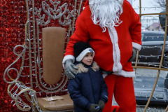 Mikołaj pozuje do zdjęcia z chłopcem. Stoją we wnetrzu bombki - ozdoby. Za nimi tron.