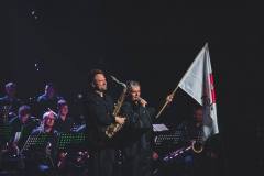 W centrum kadru Paweł Zielak i trzymający flagę Konina Krzysztof Pydyński. W tle muzycy Big Bandu.