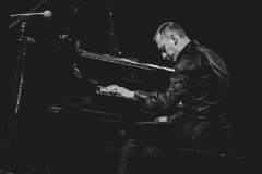 Dominik Wania przy fortepianie. Zdjęcie czarno-białe.