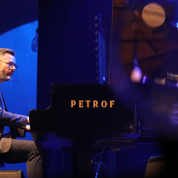 Pianista przy fortepianie Petrof.