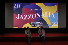 Na brzego sceny Kina Konesera siedzi dwóch mężczyzn. Trwa rozmowa. W tle wyświetlony slajd Jazzonalia.