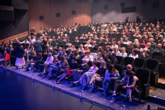 Zdjęcie ze sceny z widokiem na publiczność zasiadającą w fotelach.