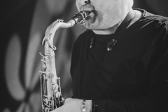 Zdjęcie portretowe grającego na saksofnie Dariusz Herbasza. Zdjęcie czarno-białe.