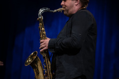Sfotografowany z lewego profilu Paweł Zielak gra na saksofonie.