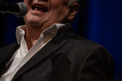 Zdjęcie portretowe. Stanisław Sojka śpiewa przy mikrofonie. Oczy przymknięte.