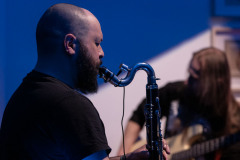 Krzysztof Matysiak sfotografowany z prawego boku gra na klarnecie. W głębi gitarzysta.