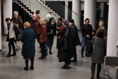Grupa osób w foyer CKiS-DK Oskard. Część ma na sobie zimową odzież. W tle białe kolumny i schody.