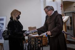 Kobieta w czarnym długim futerku z małym czarnym plecakiem odbiera książki z rąk Jeremiasza Szewczyńskiego.