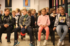 Zdjęcie grupowe dzieci siedzących na krzesłach.
