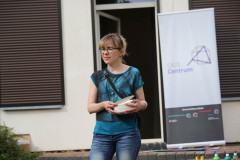 Renata Bielińska trzyma papierowe tacki. W tle budynek CKiS przy Okólnej. Zasłonięte brązowe żaluzje. Otwarte drzwi tarasowe.