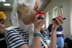 Paulina Pachulska-Wojdak sfotografowana z prawego profilu w pasiastej koszulce i nosem klowna. Robi makijaż.