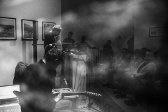 Muzycy na scenie przed publicznością. Zdjęcie wykonane zza ciemnego materiału.