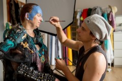 Marcin Urzędowski podczas malowania makijażu rudowłosej kobiecie. Ubrana jest ona w  strój wojowniczki.