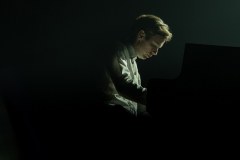 Mrok, a w środku kadru oświetlona postać Bartka Wąsika pochylonego nad klawiaturą.