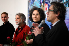 Zbliżenie na bohaterów wystawy z kwiatami i Roberta Brzęckeigo z mikrofonem. Natalia Wegner patrzy w obiektyw.