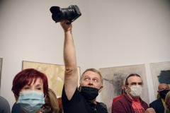 Zdjęcia robi Jerzy Sznajder, Aparat trzyma w uniesionej wysoko ponad głowami ręce.