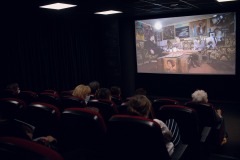 Ludzie zgromadzeni w sali kinowej przy ulicy Okólnej oglądają projekcję.
