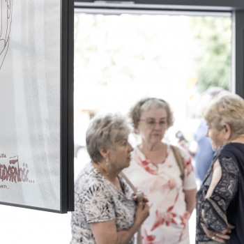 Cztery kobiety przy drzwiach wejściowych podczas rozmowy. Po lewej fragment plakatu z podobizną lecha Wałęsy i napisem Adrzej Wajda, Solidarność, Solidarność, Solidarity, Solidarity.