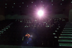 Rozbłysk światła i publiczność siedząca w sali widowiskowej. Zdjęcie zrobione z dolnych rzędów.