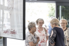 Cztery kobiety przy drzwiach wejściowych podczas rozmowy. Po lewej fragment plakatu z podobizną lecha Wałęsy i napisem Adrzej Wajda, Solidarność, Solidarność, Solidarity, Solidarity.
