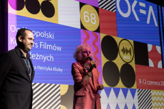 Od lewej: Grzegorz Jaroszuk i Paulina Pachulska-Wojdak z mikrofonem. Za ich plecami wyświetlony slajd z grafiką OKFA.