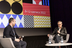 W fotelach na scenie siedzą Grzegorz Jaroszuk i Łukasz Maciejewski. Za nimi fregment slajdu  z napisem 9-12 czerwca 2022.