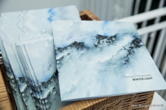 W wiklinowym koszu umieszczone są katalogi wystawy Tomasz Olszewski Winter Light