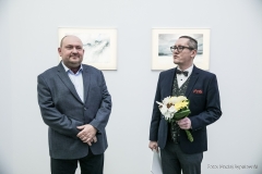 Po lwej Tomasz Olszewski, po prawej kurator Robert Brzęcki z bukietem kwiatów w lewej dłoni
